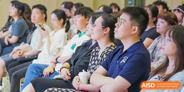 A diverse group of students and staff members listen to a guest speaker during an assembly at Griffin International Academy.