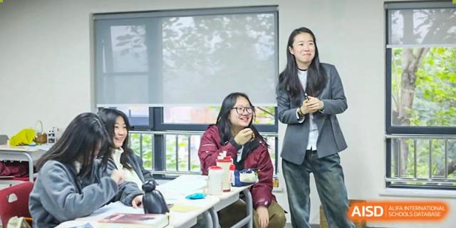 Two female students share a laugh while working together on a laptop in a bright classroom at Griffin International Academy.