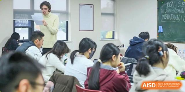 A group of students sits at a table and takes notes during an academic workshop or lesson at Griffin International Academy.