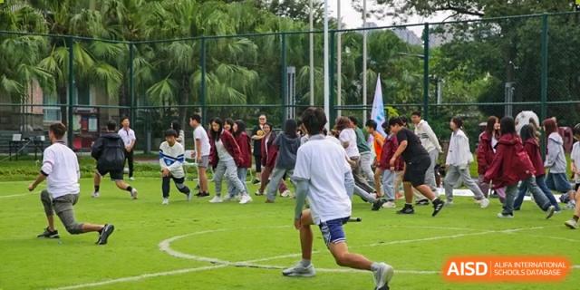 A large group of students in PE uniforms participate in an organized field activity on the grass at Griffin International Academy.