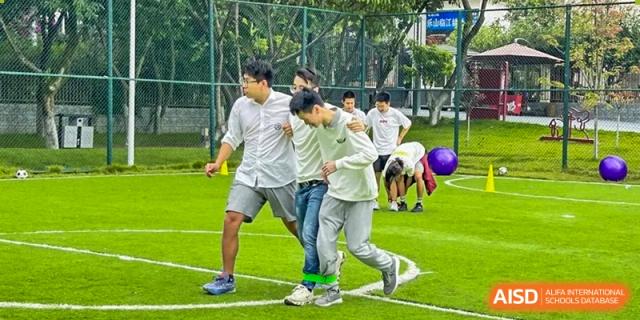 Three male students participate in a three-legged race during an outdoor sports day event at Griffin International Academy.