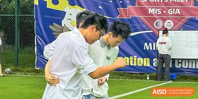 Two male students in white shirts work together closely during an outdoor team-building exercise at Griffin International Academy.