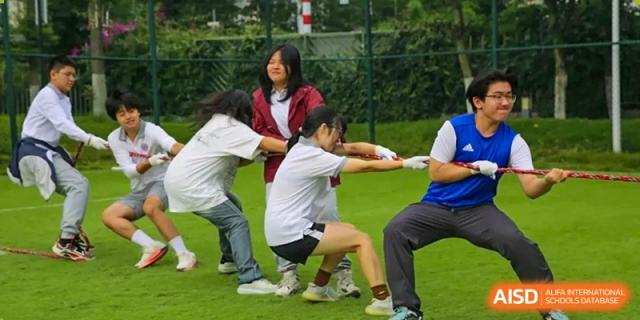 A team of students works together during a competitive game of tug-of-war on the school field at Griffin International Academy.