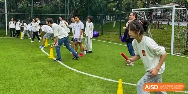 Students engage in various relay races and physical challenges on a bright green outdoor field at Griffin International Academy.