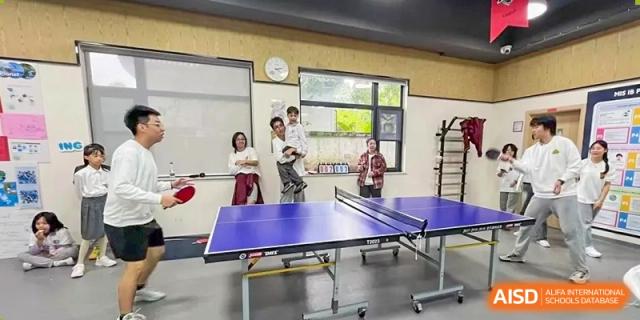 Two students play a competitive match of table tennis in an indoor recreational facility at Griffin International Academy.