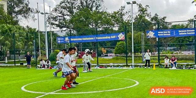 Students in white uniforms participate in a group race on an outdoor green sports field at Griffin International Academy.