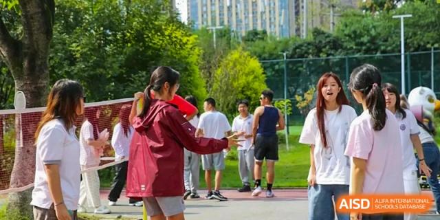 A female student in a maroon jacket prepares to throw a ball during an outdoor physical education class at Griffin International Academy.