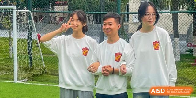Two students and a teacher smile and pose for a friendly photo during an outdoor school event at Griffin International Academy.