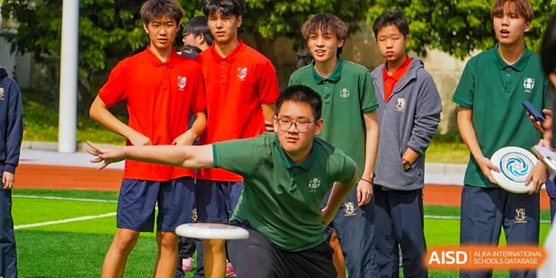 A student in a green polo shirt prepares to throw a frisbee during an active outdoor physical education class at St Bees Dongguan.
