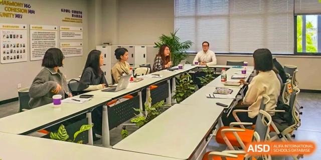 A professional development meeting with staff seated around a modern conference table at Beijing No. 35 High School International Department.