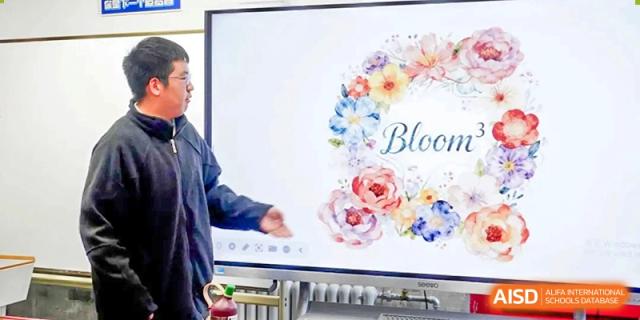 A speaker presents a floral-themed slideshow titled "Bloom" on a digital monitor at Beijing No. 35 High School International Department.