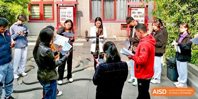 A group of students in red uniforms holds an outdoor meeting in a traditional courtyard at Beijing No. 35 High School International Department.