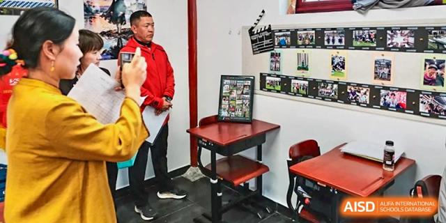 A staff member stands next to a commemorative display of student achievements and photos at Beijing No. 35 High School International Department.