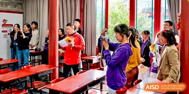 A student focuses on filming a school performance with a smartphone in a classroom at Beijing No. 35 High School International Department.