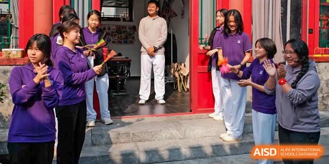 Students gather by a red door for a traditional cultural performance on campus at Beijing No. 35 High School International Department.