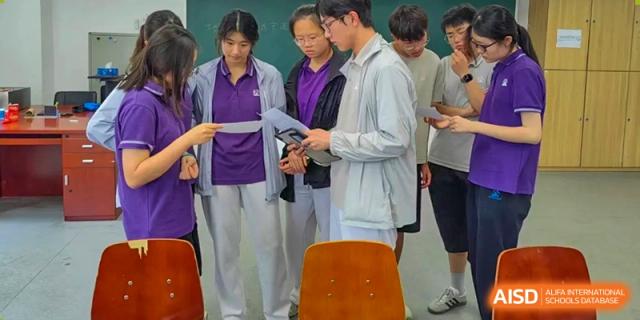 Students review a document together during a collaborative peer workshop in a hallway at Beijing No. 35 High School International Department.