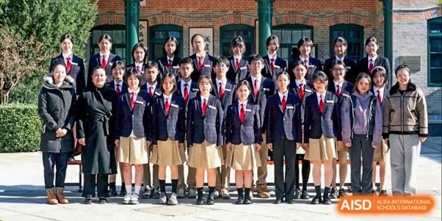 A large group of students in formal school uniforms poses for a class portrait in a traditional courtyard at Beijing No. 35 High School International Department.
