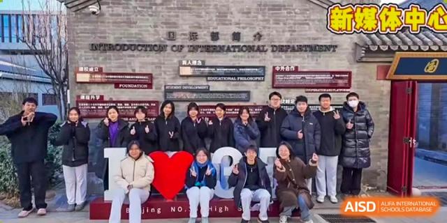 Students pose with a large red heart prop for a commemorative group photo in front of a campus building at Beijing No. 35 High School International Department.
