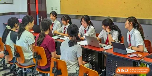Students work together in a computer lab using laptops for a collaborative research project at Beijing No. 35 High School International Department.
