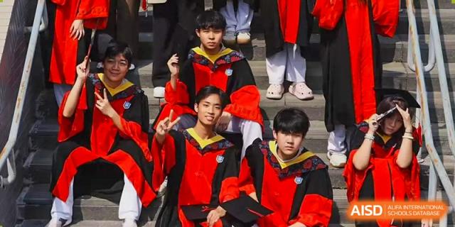 Students in graduation gowns and caps smile and celebrate on stage at Beijing No. 35 High School International Department.
