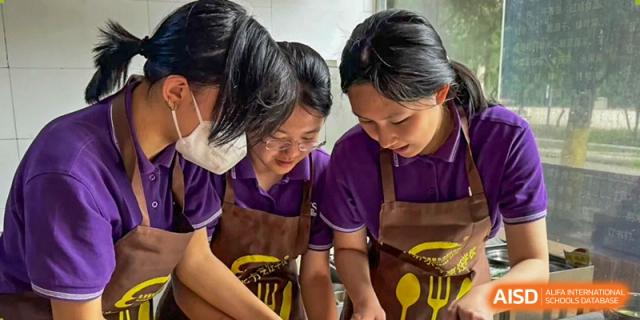 Two female students in purple aprons work together on a hands-on project during a workshop at Beijing No. 35 High School International Department.