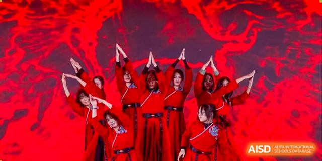 Students in vibrant red costumes perform a synchronized dance with traditional hand gestures during a cultural showcase at Beijing No. 35 High School International Department.