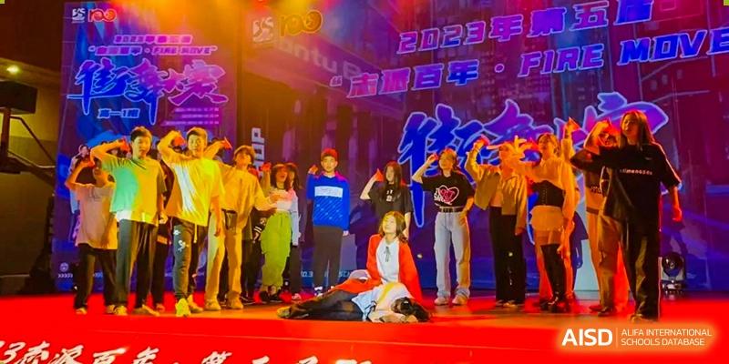 Students perform a dramatic musical routine on a stage with vibrant purple and orange lighting at Beijing No. 35 High School International Department.