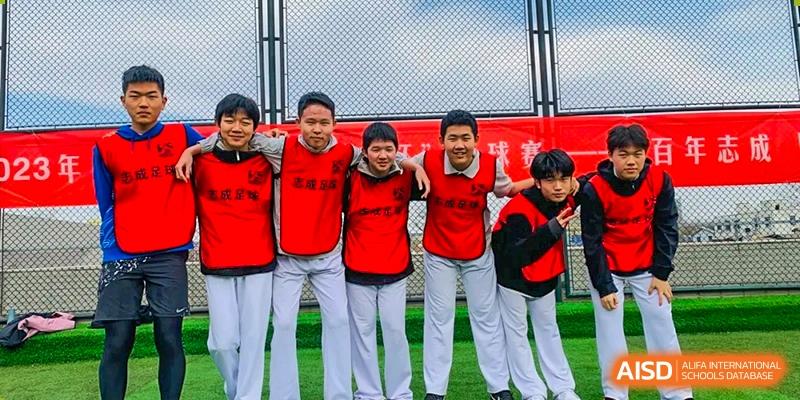 A group of students in red athletic vests pose together with smiles on the sports field at Beijing No. 35 High School International Department.
