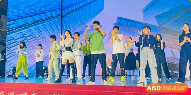 A student group performs a modern dance routine in casual attire on a brightly lit stage at Beijing No. 35 High School International Department.