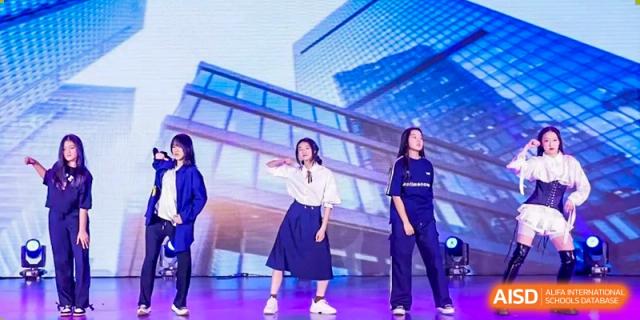 Two students perform a contemporary dance routine in front of a modern glass building at Beijing No. 35 High School International Department.