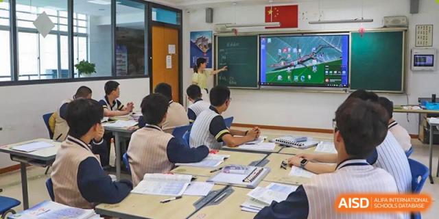 Teacher explaining a lesson using a digital screen while students follow along at their desks, highlighting interactive teaching methods and modern classroom learning at Xiamen ITG-SUIS High School