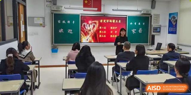 Students sit attentively as a teacher presents a lesson using a digital screen and chalkboard in a modern classroom at Xiamen ITG-SUIS High School