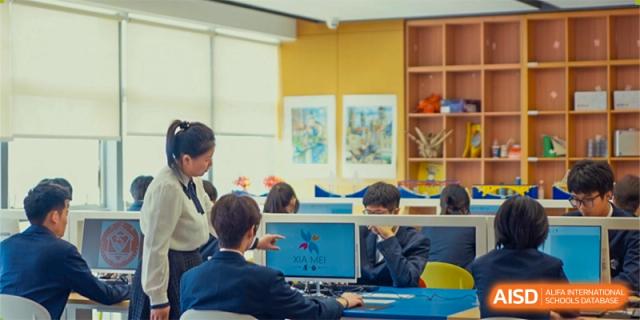 Students collaborate during a classroom activity using a digital display and teamwork skills at Xiamen ITG-SUIS High School