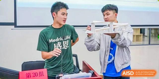 Two students demonstrate and examine a science project using lab equipment during an interactive classroom activity focused on hands-on learning at Xiamen ITG-SUIS High School