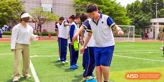Students walking carefully in a line while holding ropes during a coordination and balance game, promoting teamwork, discipline, and physical development at Xiamen ITG-SUIS High School