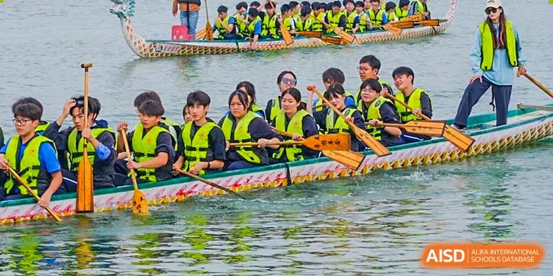 Students wearing life jackets rowing together in a dragon boat on the water, showing teamwork, coordination, and school spirit during an organized water sports activity at Xiamen ITG-SUIS High School