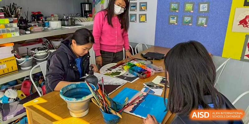 Students participating in an art class while painting at desks with guidance from a teacher, encouraging creativity, hands-on learning, and artistic expression at Xiamen ITG-SUIS High School