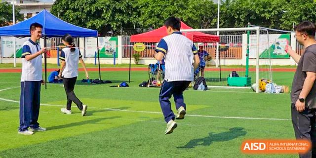 Student jumping on the artificial turf during an outdoor physical education activity, showing energy, balance, and active participation in school sports training at Xiamen ITG-SUIS High School