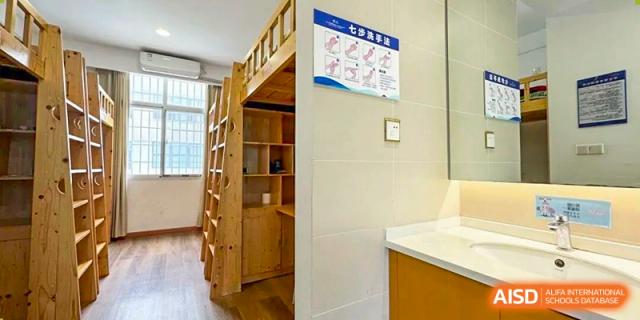 An organized student dorm room entrance showing wooden bunk beds, personal storage areas, and safety signage designed for comfortable boarding life at Xiamen ITG-SUIS High School
