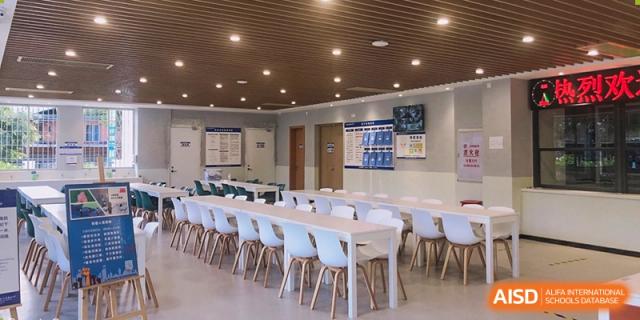 A spacious school dining hall with neatly arranged tables and chairs prepared to serve students daily meals in a bright and orderly environment at Xiamen ITG-SUIS High School
