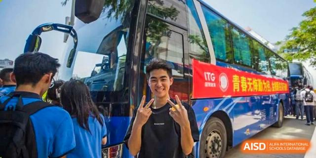 A smiling student poses with hand gestures in front of a school bus, capturing school spirit and student life during an outdoor activity at Xiamen ITG-SUIS High School