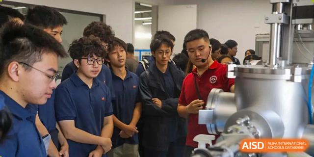 A group of students listens intently to a presentation, with one student wearing a head-mounted microphone during an academic seminar at Huafu International Department.