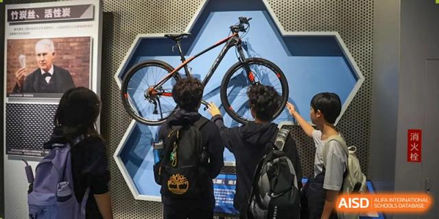 Students gather around a high-performance mountain bike mounted on a display wall to study its engineering and design at Huafu International Department.