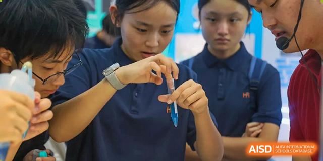 A female student focuses on a science experiment, carefully mixing a blue liquid in a test tube during a laboratory session at Huafu International Department.