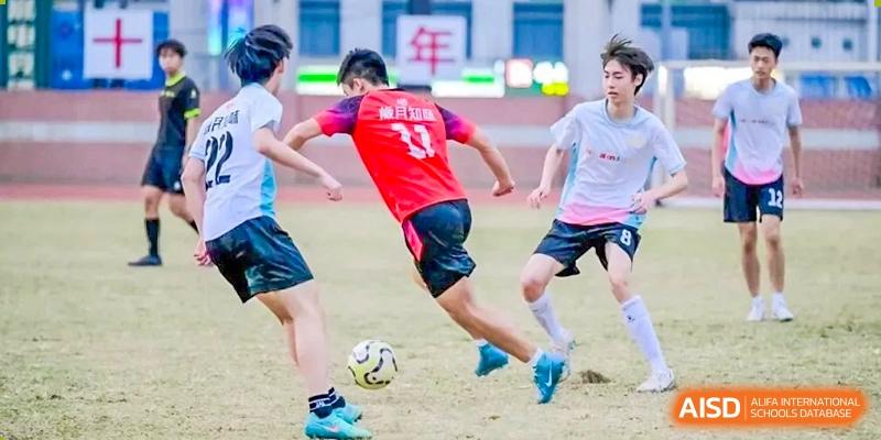 A soccer player in a red jersey with the number 33 dribbles a ball down the field while being closely guarded by opponents during a game at the Huafu International Department.