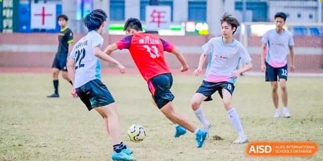 A soccer player in a red jersey with the number 33 dribbles a ball down the field while being closely guarded by opponents during a game at the Huafu International Department.