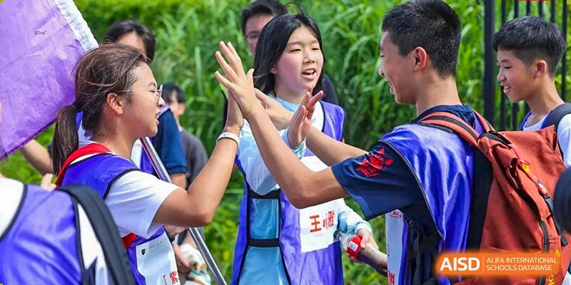 A student in a blue vest gives a high-five to a peer, celebrating a moment of teamwork and joy during a sports day at the Huafu International Department.