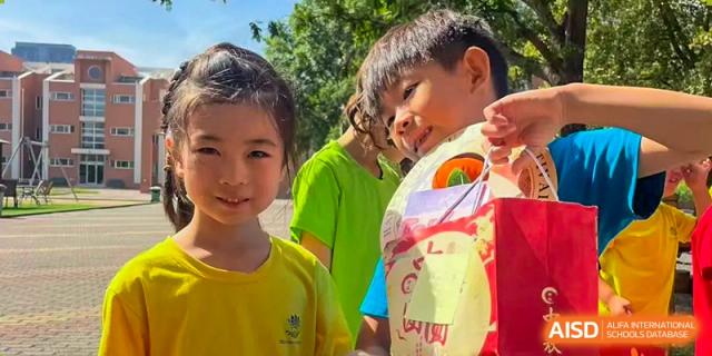 Smiling young students gather together outdoors for a group photo during a school event at TEDA International School Tianjin.