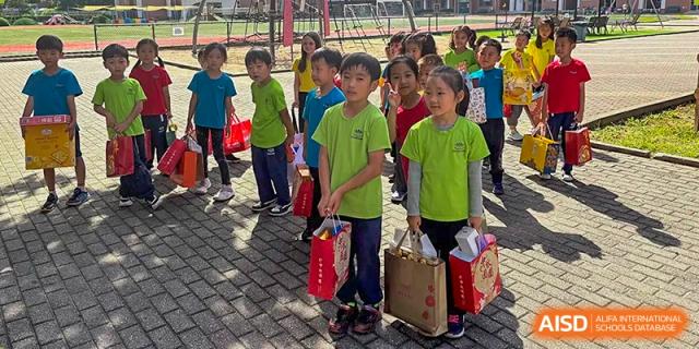 Students carry red gift bags and paper crafts while walking together after a school celebration at TEDA International School Tianjin.