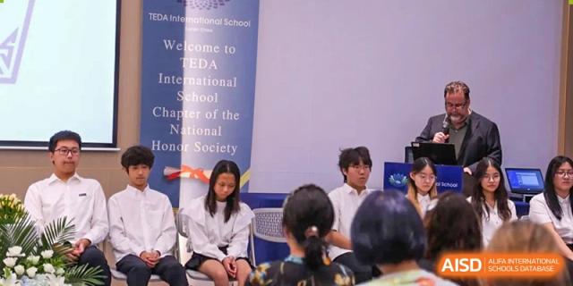 Students sit in a circle during a formal meeting for the National Honor Society chapter in the school auditorium at TEDA International School Tianjin.